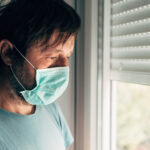 Depressed man with protective mask in self-isolation quarantine