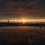 Man fishing at sunrise on the line of horizon