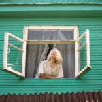 Woman near window looking up facing the sunrise at morning.